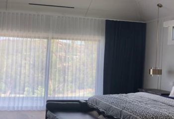 Spacious Los Angeles bedroom featuring custom motorized draperies and sheer curtains.